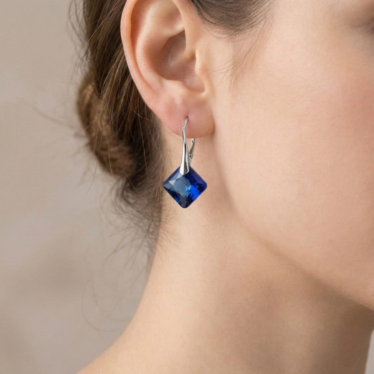 Kolczyki z kryształami Bermuda Blue w srebrnej oprawie. Ujęcie eksponuje nasycony błękit oraz elegancką wiszącą formę przy twarzy.