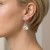 Kolczyk z jasnym kryształem Crystal prezentowany na uchu modelki